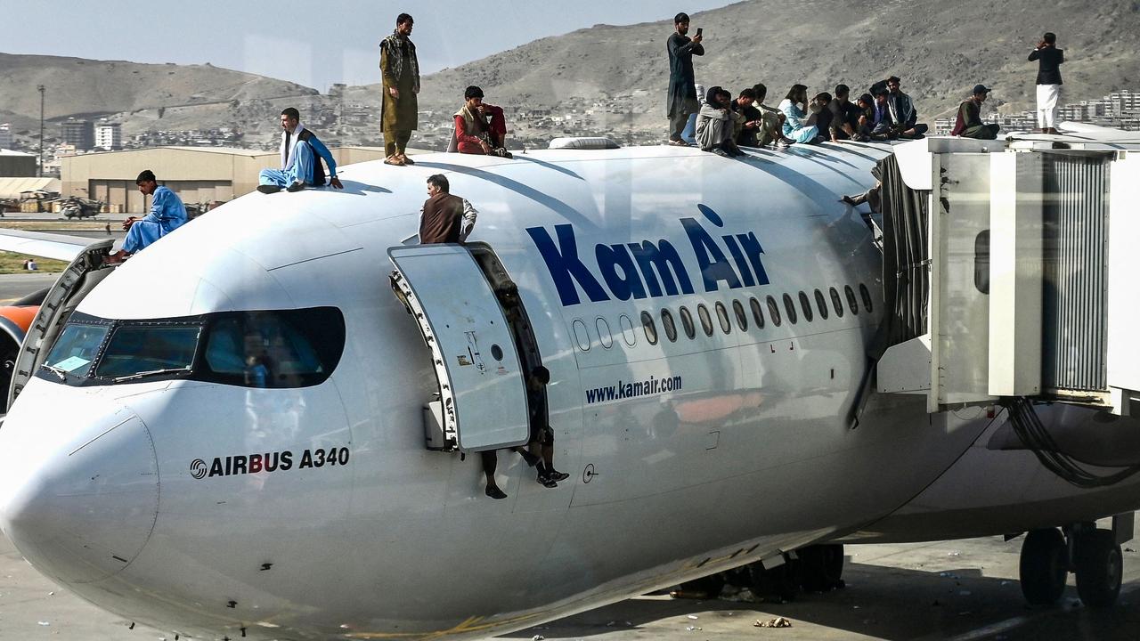 Afghan people climb on a plane as they wait at the airport in Kabul on August 16, 2021. Picture: Wakil Kohsar/AFP