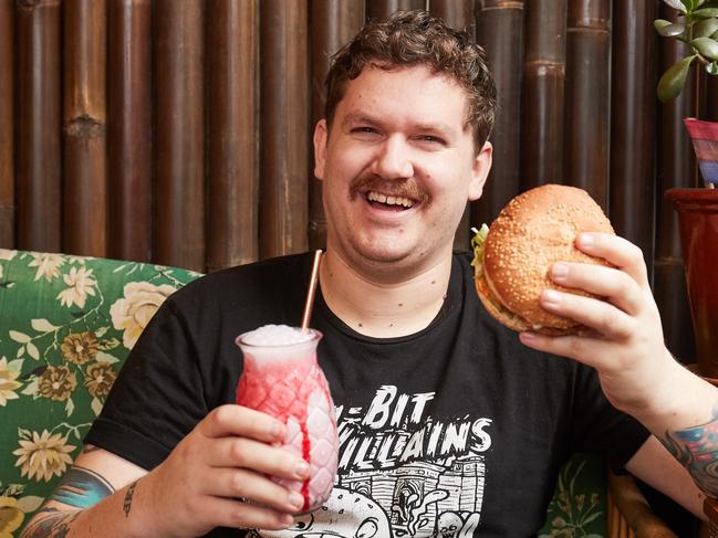 Owner, Liam Hughes poses for a picture at Two Bit Villians in Adelaide, with a popular vegan option; Seitan Buffalo "Chicken" Burger and a Strawberry Milkshake, Friday, July 12, 2019. Picture: MATT LOXTON