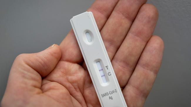 A used rapid antigen test, also known as a lateral flow test showing a positive test result for the Covid-19 coronavirus is photographed in Berlin on January 22, 2022. - Taking a test involves doing swab from inside your nostril or in your throat, depending on the test you are using, before mixing the swab with solution and dripping it onto a container with a test strip with antibodies specific to the Covid-19 virus painted on it in a thin line. If the testing strip detects the virus, it shows up as a red line next to the âTâ on the container, the line next to the âCâshould always be visible. (Photo by Odd ANDERSEN / AFP)