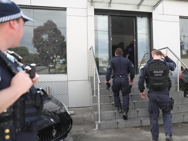 Police raided and searched a business premises on the Lower North Shore, smashing one door open and searching cars. Picture: John Grainger