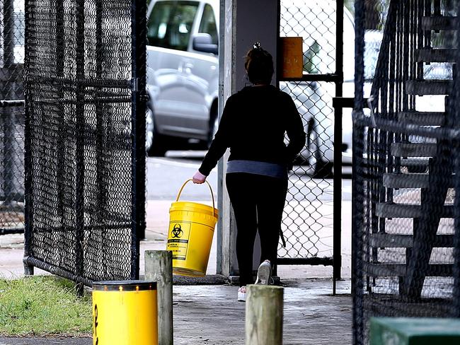 A person collects syringes from the ground in a carpark in Richmond.