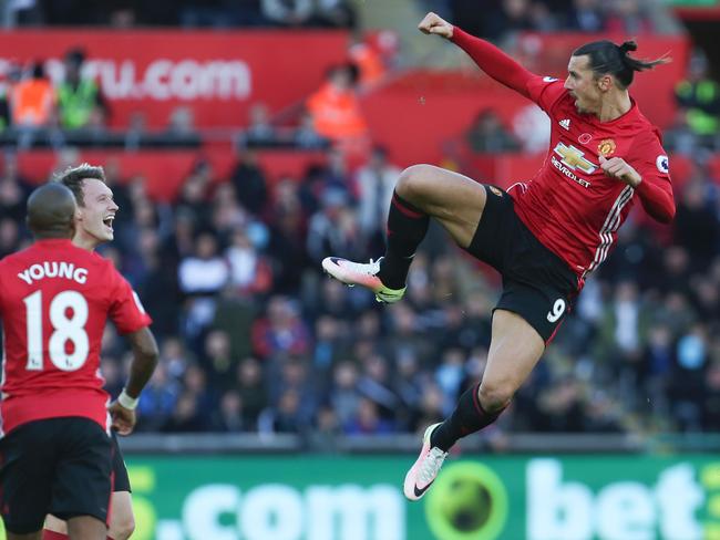 Manchester United's Swedish striker Zlatan Ibrahimovic (R) jumps and kicks the air as he celebrates scoring his team's second goal with Manchester United's English midfielder Ashley Young (L) and Manchester United's English defender Phil Jones during the English Premier League football match between Swansea City and Manchester United at The Liberty Stadium in Swansea, south Wales on November 6, 2016. / AFP PHOTO / Geoff CADDICK / RESTRICTED TO EDITORIAL USE. No use with unauthorized audio, video, data, fixture lists, club/league logos or 'live' services. Online in-match use limited to 75 images, no video emulation. No use in betting, games or single club/league/player publications. /