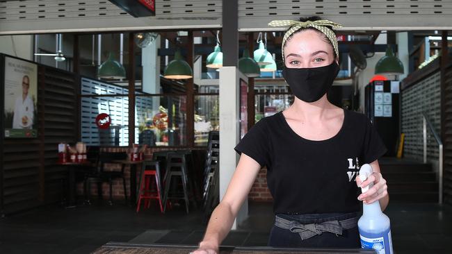 Manager of Grill'd Cairns Jessica Bagley disinfects tables, chairs and menus before the Esplanade restaurant reopened to dine in customers last week. Foot traffic along the esplanade has come to a standstill. Picture: Brendan Radke