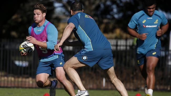 Michael Hooper takes on the defence of Wallabies coach Michael Cheika during training on Friday.