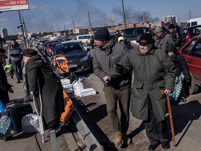 Residents of Irpin and Bucha are helped by members of the Ukrainian military as they evacuate via a destroyed bridge in Irpin, Ukraine. Picture: Getty Images