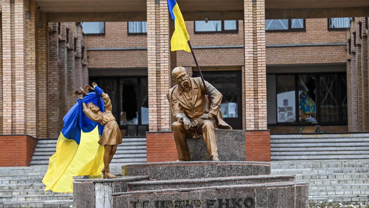 Ukrainian flags placed on statues in a square in Balakliya, Kharkiv region, as Ukraine mounts a major offensive against occupying Russian forces. (Photo by Juan BARRETO / AFP)