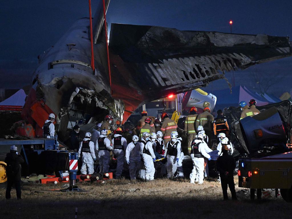 Firefighters and rescue personnel carry the body of a victim near the scene where a Jeju Air Boeing 737-800 series aircraft crashed and burst into flames at Muan International Airport. Picture: Jung Yeon-je / AFP