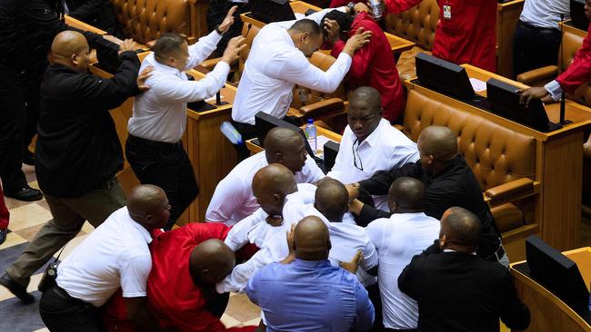 Economic Freedom Fighters (EFF, in red) party members of parliament are physically removed from the South African parliament. Picture: AFP