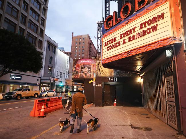 A man walks with two dogs past the shuttered Globe Theatre in Los Angeles. Picture: Getty Images/AFP