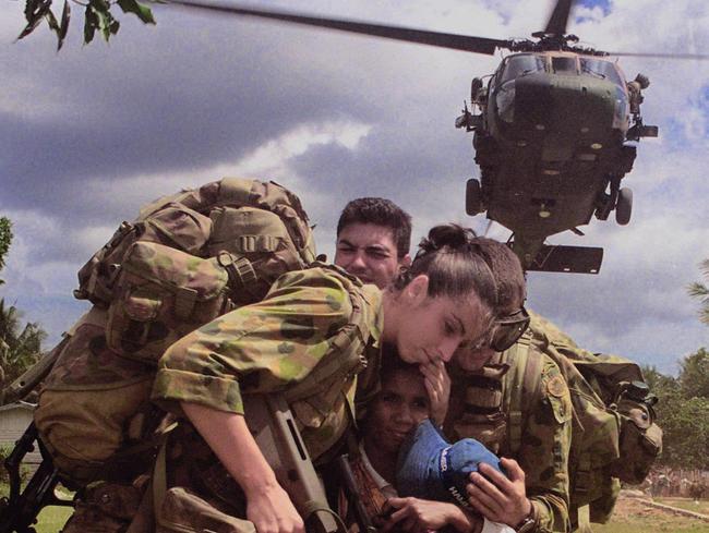 MAY 11, 2001 : Medic Private Tammy Smithson shelters baby during Medivac in Grotu in Southern East Timor 11/05/01, suffering malaria flown by Black Hawk to Suai for medical treatment. Pic W02 Al Green. Australian Armed Forces / Army / Soldier / Interfet