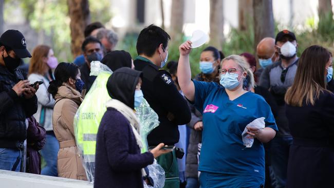 NSW Health staff hand out masks to people queuing at the Olympic Park Vaccination Hub in Sydney. Picture: NCA NewsWire / Gaye Gerard