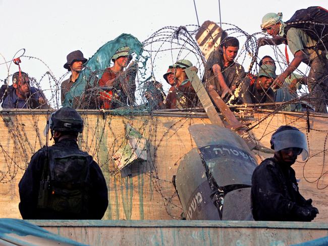 Israeli security forces force their way on to a roof of a synagogue in the Gaza Strip, where dozens hold out against their evacuation in 2005. AFP