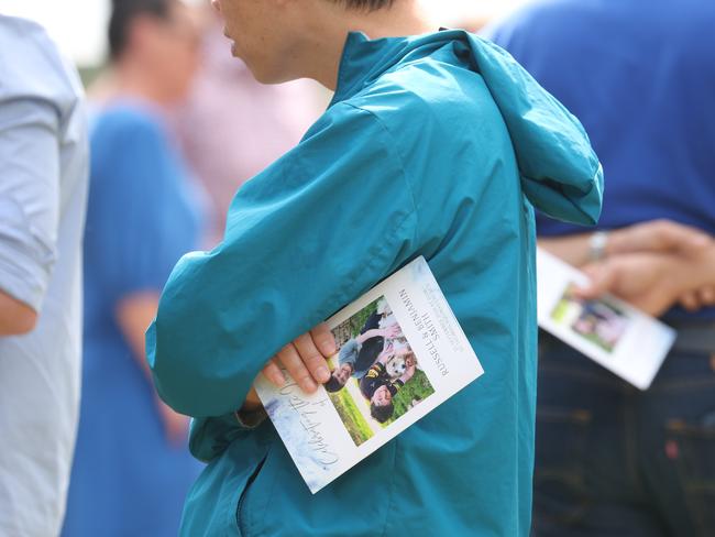 A mourner holds the order of service, bearing the boys’ picture, at the funeral. Picture: Rohan Kelly