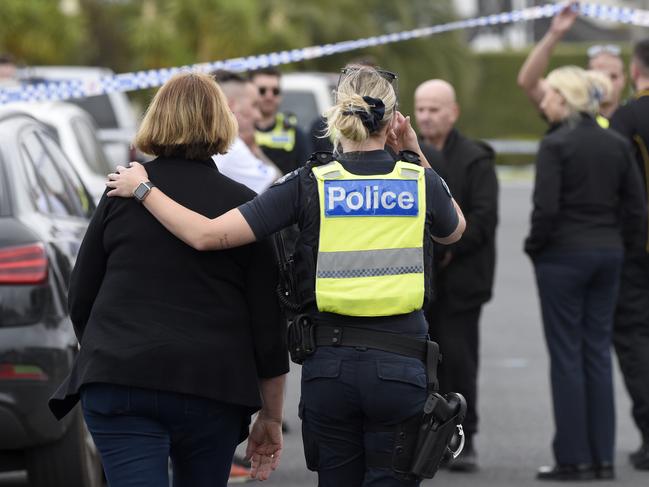 A police officer comforts a woman at the scene of the shooting. Picture: Andrew Henshaw
