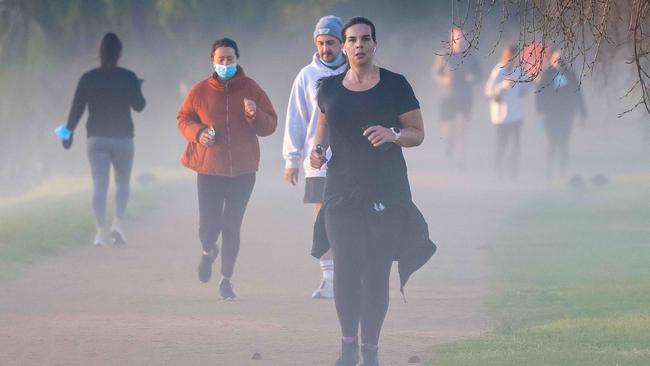 People exercise in the early morning around Albert Park in Melbourne on Thursday. Picture: Ian Currie