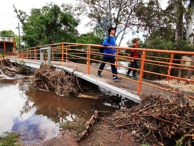 Children cross a footbridge clogged with flood debris in Euroa. Picture: Aaron Francis/The Australian