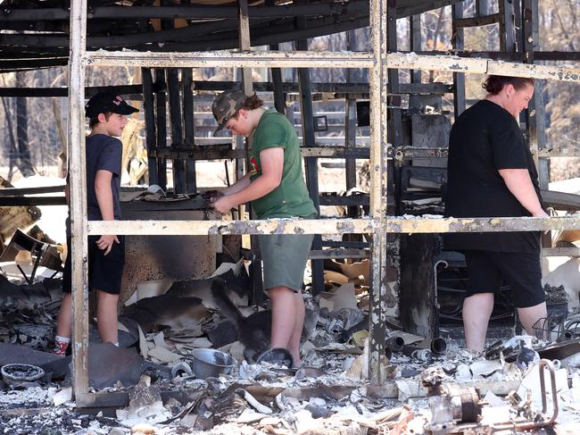 Sarah Windsor and her kids, salvaging items from their burnt-out home lost in the Tara fires. Picture: Liam Kidston