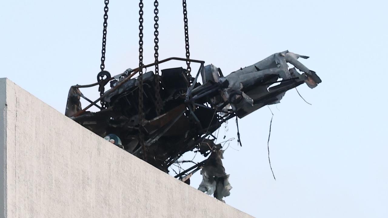 A large crane lifts the wreckage of a Robinson R44 helicopter off the roof top of the Double Tree Hilton hotel into a skip bin, before lowering it to the Cairns Esplanade. The chopper was stolen from Nautilus Aviation and crashed onto the roof at about 1:50am on Monday. Picture: Brendan Radke