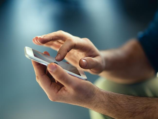 Male hands typing on smartphone.