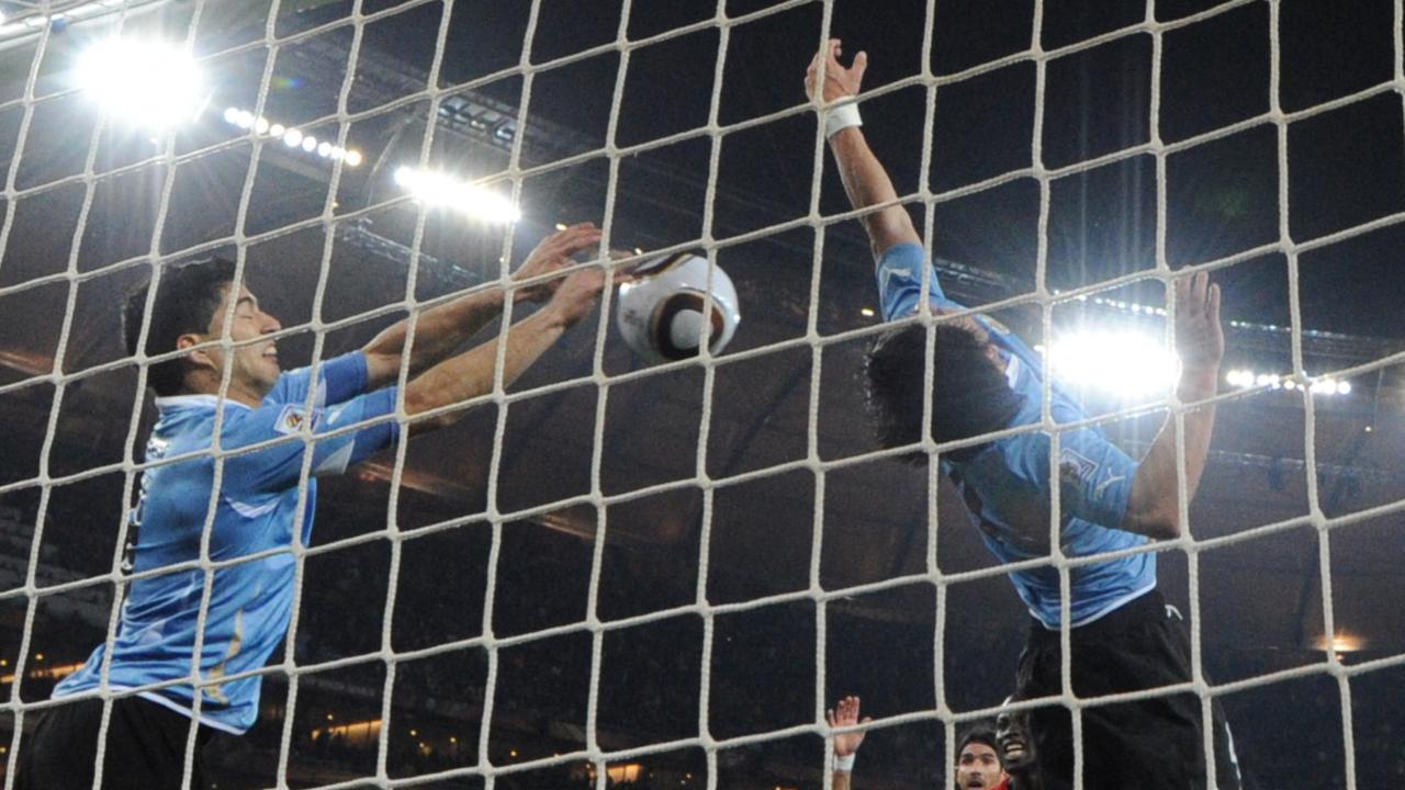 In this file photo taken on July 2, 2010 Uruguay's striker Luis Suarez (L) stops the ball with the hand leading to a red card and a penalty for Ghana during the extra-time of their 2010 World Cup quarter-final match. (Photo by ROBERTO SCHMIDT / AFP)