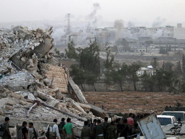 Syrian regimen forces gather at the Kindi Hospital as smoke billows following aistrikes on Aleppo. Picture AFP
