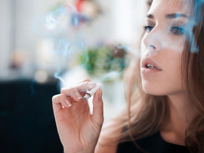 The thoughtful woman smokes a cigarette.