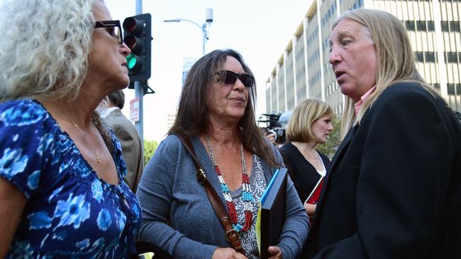 Janet Wolfe, left, and Marla Randall, sisters of the late guitarist and songwriter Randy Wolfe, speak with rock journalist Michael Skidmore outside court after the decision. Picture: AFP