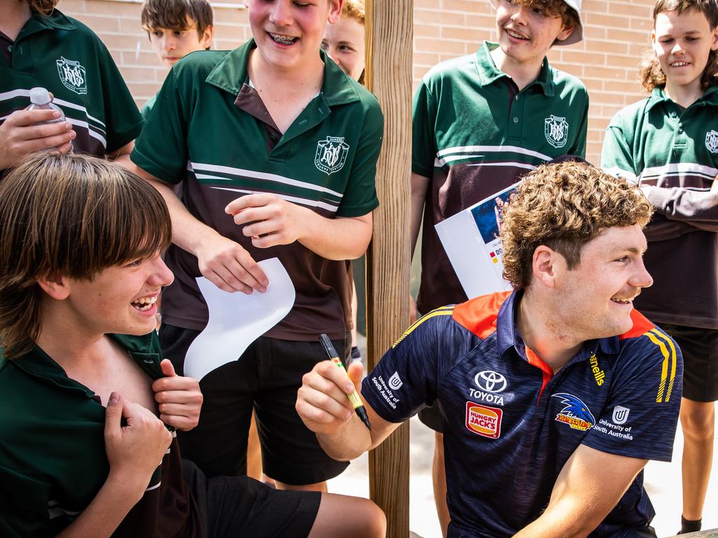 Crow Harry Schoenberg signs the chest of a student from Waikerie High School during a visit for the The Advertiser Foundation Christmas Kids Appeal. Picture: Tom Huntley