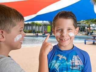 SUN SAFE: Harlow Axisa, 7, applies sunscreen to his brother Cooper, 8, at the Bluewater Lagoon. Picture: Emma Murray