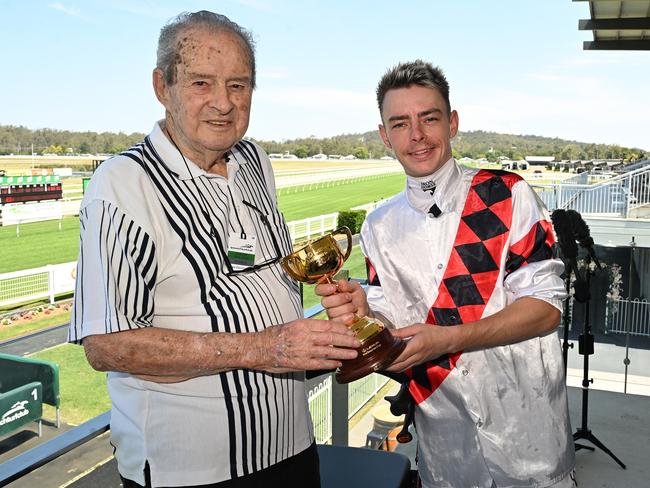 Robbie Dolan shows off his Melbourne Cup trophy to 91-year-old Ipswich Turf Club member Brian Christensen. Picture: Grant Peters/ Trackside Photography