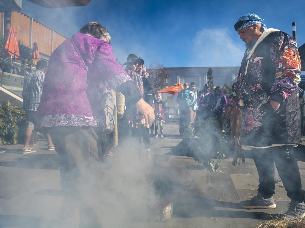 Barbara Walker lets the smoke waft over her as Jarowair Wakka Wakka man Conrad Bauwens conducts a Smoking Ceremony at the NAIDOC arts and craft market at Grand Central, Saturday, July 9, 2022. Picture: Kevin Farmer