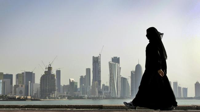 A Qatari woman walks in front of the city skyline in Doha, Qatar, which is now cut off from its Gulf neighbours. Picture: Kamran Jebreili/AP