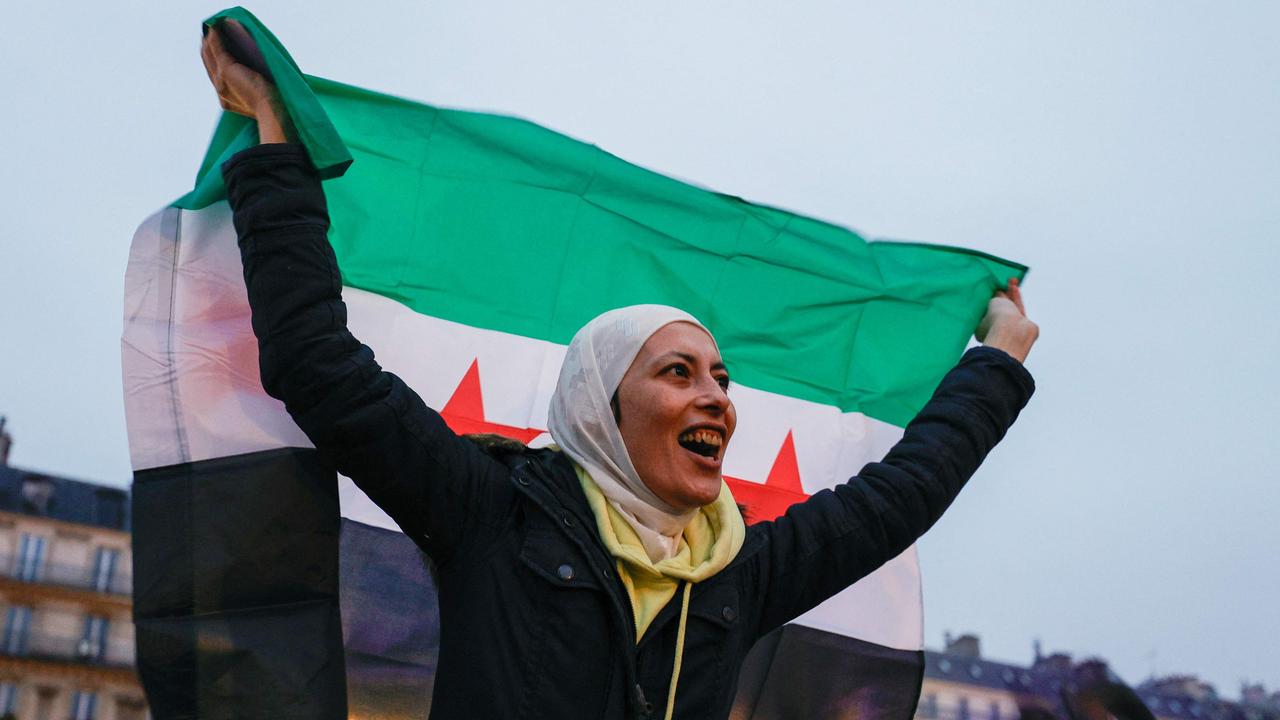 A protester cheers as she holds a Syrian independence-era flag during a rally in support of the Syrian people and in celebration of the December 8, 2024, fall of Syrian president Bashar al-Assad, at the Place de la Republique, in Paris, on December 14, 2024. (Photo by Xavier GALIANA / AFP)