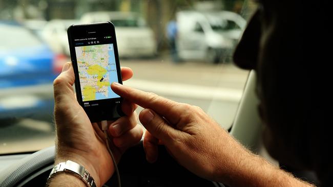 Ex taxi driver Steve who now is working for Uber with his own car pictured in Sydney today keeping up to date on his mobile, looking for fares.