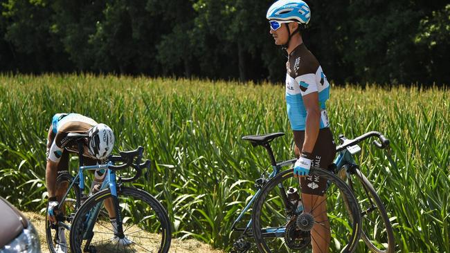 France's Alexis Vuillermoz (right) stands by the stage's first cobblestone section after handing a wheel to France's Romain Bardet who suffered a puncture. Picture: AFP