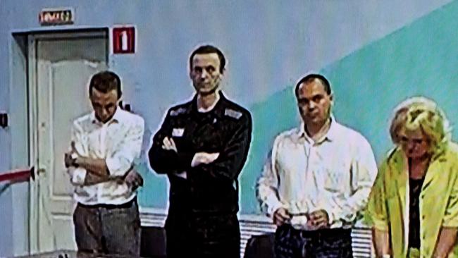 A screen shows Alexei Navalny (second left) as he listens to his verdict over a series of extremism charges at the IK-6 penal colony. Picture: AFP