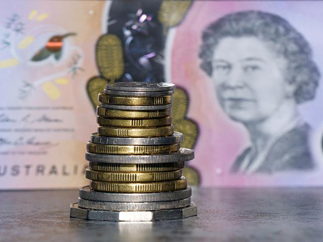 Australian coins stacked in front of an Australian five dollar bill in a panoramic format with image distortion. The new issue is designed to deter counterfeiting, the note is polymer and water resistant. cash money generic