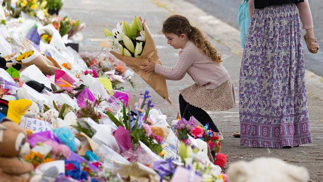 A girl adds to the pile of tributes at Hillcrest Primary. Picture: Jason Edwards