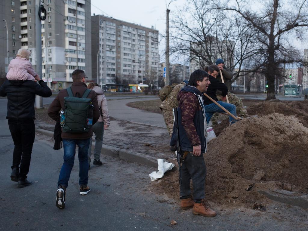 Kyivans walk by the territorial defense battalion soldiers on Friday. Picture: Anastasia Vlasova/Getty Images