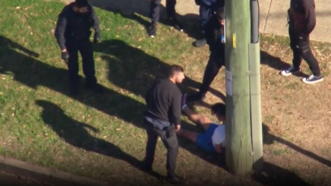 Kasey Glover, sitting handcuffed against a power pole after being arrested. Picture: Sky News.