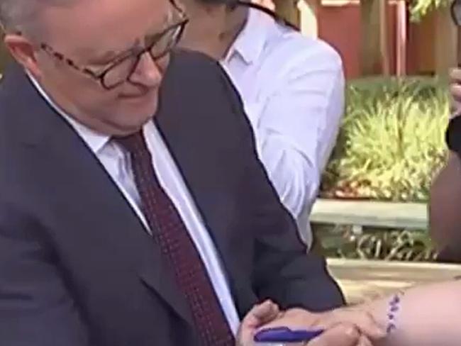 Prime Minister Anthony Albanese signs journalist's arm and his front page on the WA GST funding guarantee. Picture: ABC