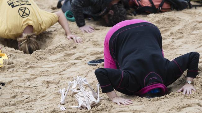 Extinction Rebellion activists bury their heads in the sand on Manly Beach. Picture: Brook Mitchell/Getty Images