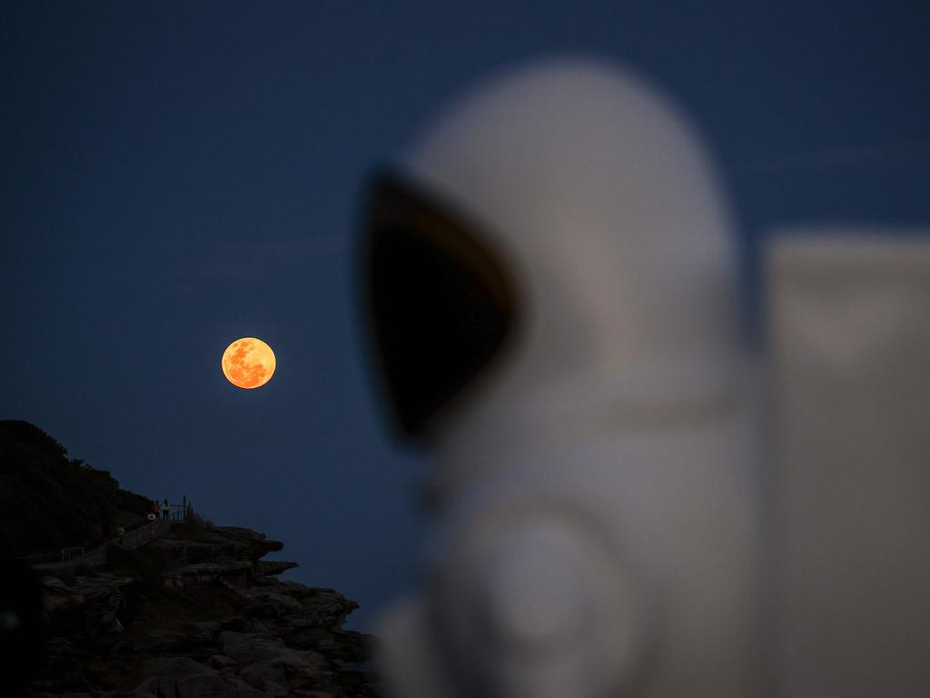 The vividly coloured moon is seen in the background behind an astronaut art installation as part of the Sculpture by the Sea exhibition near Bondi. Picture: David Gray/AFP