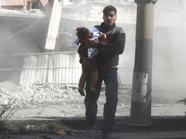 A man carries a girl injured in government bombing in the rebel-held town of Hamouria, in the besieged Eastern Ghouta region. Picture: Abdulmonam Eassa/AFP