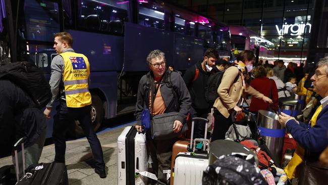 Australian officials help passengers at London’s Heathrow airport as they are repatriated from Israel on Tuesday. Picture: Getty Images