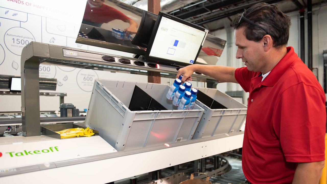 A worker packs groceries at a Takeoff Technologies automated fulfilment centre.