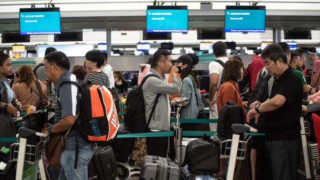 Passengers wait in line at check-in counters at Hong Kong's International Airport. Flights are departing Hong Kong airport largely on schedule this morning. Picture: Philip Fong/AFP