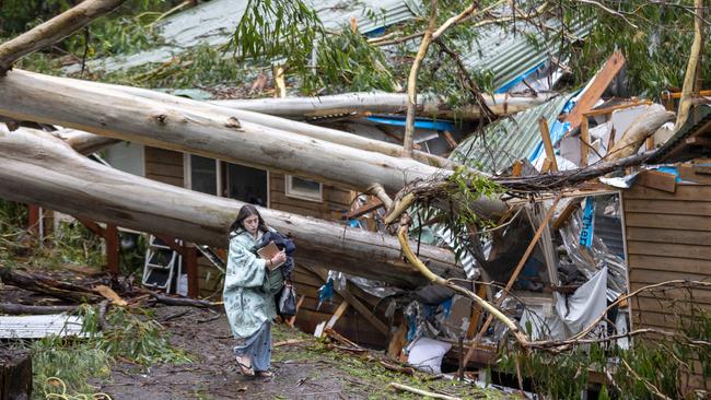 A young girl collects belongings after her home was crushed by a falling tree in Olinda. Picture: David Geraghty