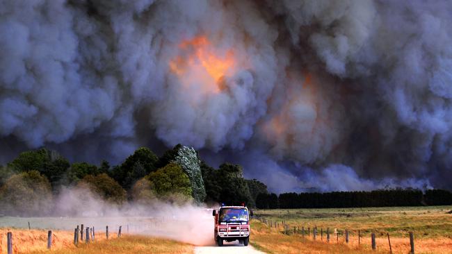 A fire truck drives away from the smoke and flames of Black Saturday bushfires at Labertouche. Picture: Alex Coppel