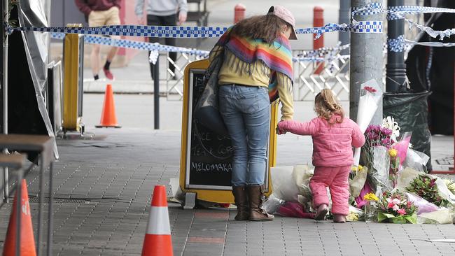 A woman and child place flowers near the scene of a fatal stabbing in North Hobart. Picture: LUKE BOWDEN